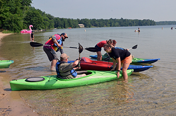 Kayakers prepare to launch from the beach at Interlochen State Park.