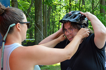 A participant gets help adjusting her bike helmet at DiversAbility Day at Interlochen State Park.