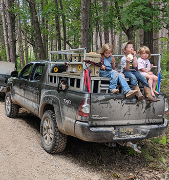 The kids take a lunch break on Elijah Keller’s truck during a bear hunting training run.