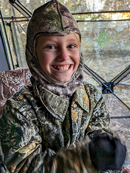 A camouflaged Olive Dean is pictured in her deer blind on the hunt. 