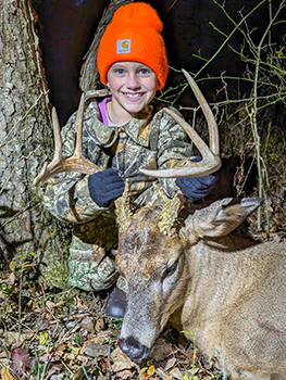 Olive Dean poses for a picture with her buck harvest in the late daylight hours in the woods of Tuscola County.