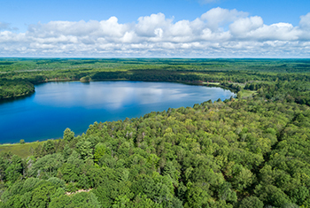 A deep blue, forest-green and summery aerial photo of Silver Lake is shown.
