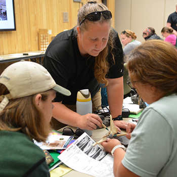 Educators gathered around a deer's jaw bone. 