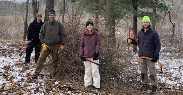 group of stewardship volunteers by brush pile in winter
