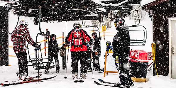 skiers loading onto ski lift with snow falling