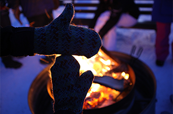 mittens making the shape of michigan backlit by a campfire