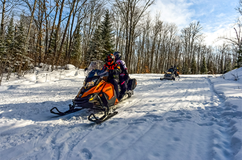two snowmobiles riding on trail