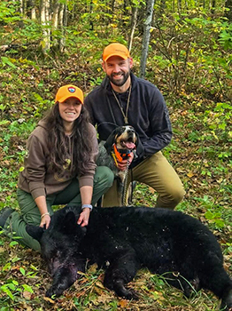 The DNR's Cody Norton, his dog B and DNR biologist Morgan Lucot are shown with Norton bear harvest.