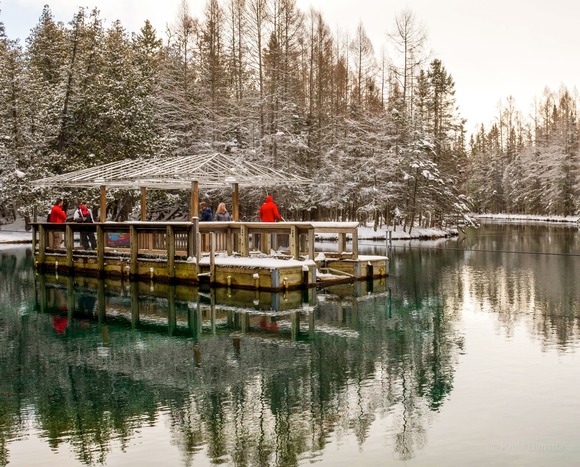 people dressed in bright orange winter coats on the snowy observation platform at Kitch-iti-kipi natural spring in Palms Book State Park