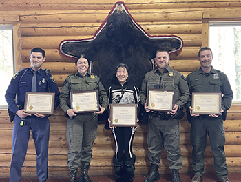 five people pose, smiling holding plaques