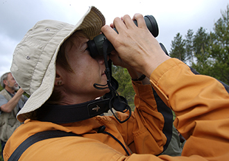 a birder holding binoculars and looking into the sky