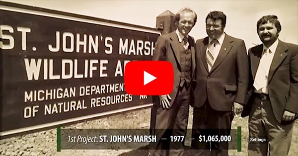 Sepia-toned still of Michigan Natural Resources Trust Fund 50th anniversary video, with three men in suits next to St. Johns Marsh sign