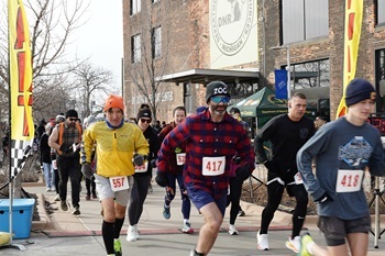Men and women, some in red-flannel plaid, some in rain gear, in the 2025 Lumberjack Run in front of the Outdoor Adventure Center