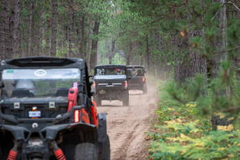 three ORVs riding on dirt-packed trail