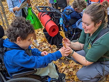 An instructor shows fallen autumn leaves to a Nature Awaits participant.