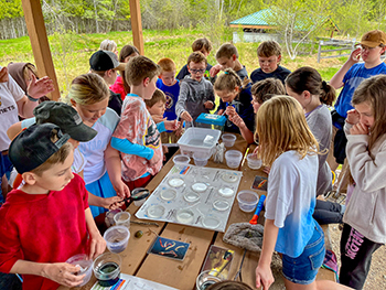 Nature Awaits students are shown gathered around a table on an outing.