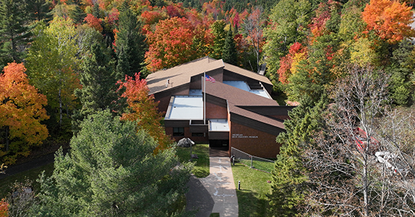 An aerial view of the Michigan Iron Industry Museum amongst trees in the fall.