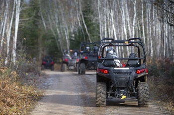 Four all-terrain vehicles driving away, single file, on a recreational ORV between Champion and Big Bay, Marquette County.
