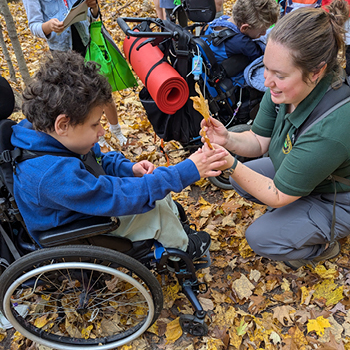 A DNR educator helping a student in a wheelchair with an activity about leaves