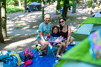 three campers smiling in their campsite