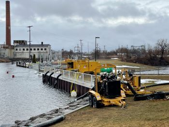 A series of pumps are being used to bring water around the Cheboygan Lock and Dam. The yellow pumps have llarge tubes feeding into the water. 