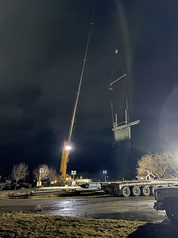 a crane operator lifts a gate high in the air Sunday evening, having just removed it (and others) from Cheboygan Dam to increase water flow