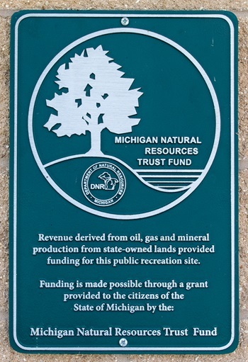 The dark green, portrait-oriented Michigan Natural Resources Trust Fund sign that is present at all Trust Fund-supported sites