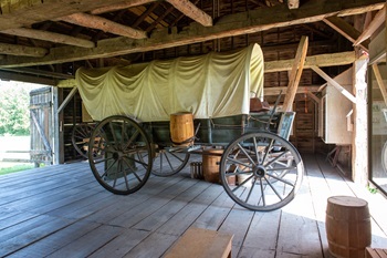 an old covered wagon with a yellow tarp stands in a barn at Cambridge Junction State Park
