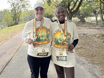 two Happy Little Trees 5K participants posing with their medals, T-shirts and bibs