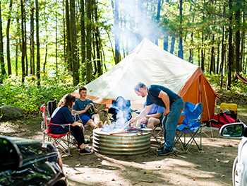 family sitting around fire with tent in background