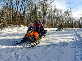 snowmobilers riding on snowy trail