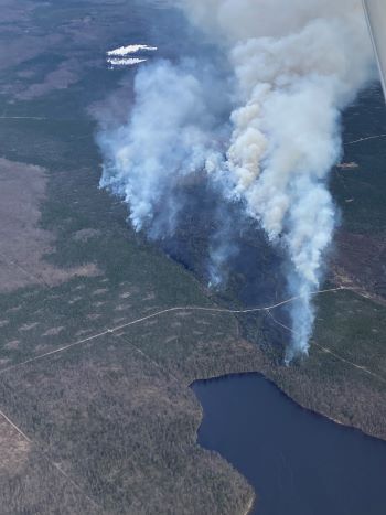 Plumes of smoke rise over green land and a flooding area during a fire May 10 in Presque Isle County.
