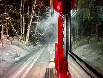 A nighttime shot shows the view from a trail groomer's cabin.