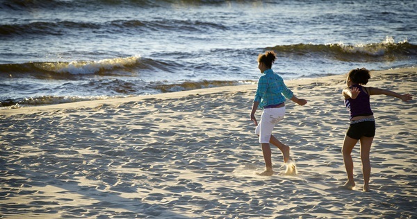 Two girls in summer clothing running on the sandy beach at Lake Michigan