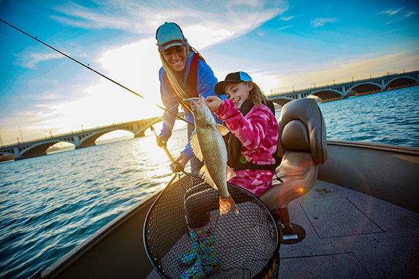 A woman and a girl show a walleye caught on Lake Huron while boating.