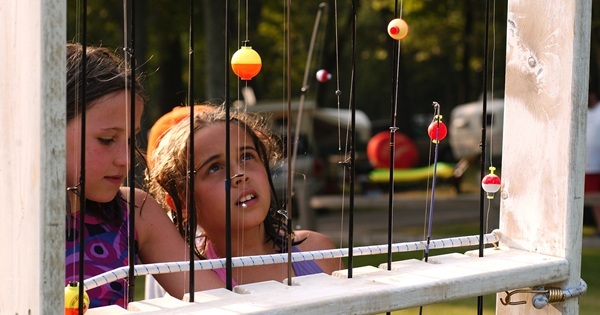 two young girls looking at a rack full of fishing poles, some tied with colorful bobbers