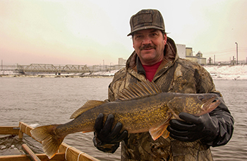 An angler holds up his walleye catch hooked on the Tittabawassee River, a Lake Huron tributary.