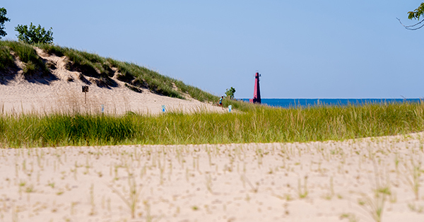 dune at Muskegon State Park with red lighthouse in the distance