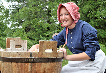 Future Historians costumed interpreter washes laundry in washtub
