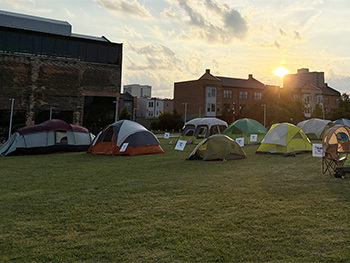 tents spread across lawn in front of brick buildings