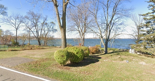 a small-acreage lot with 30 feet of lake frontage in Novi, showing road access and some trees on the lot