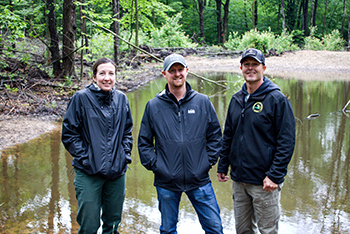 U.S. Forest Service and Michigan DNR staffers stand in front of a woodland pond created as part of the GNA efforts.