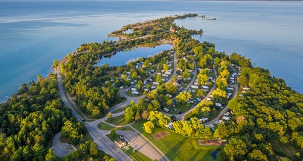 aerial view of Tawas Point State Park, showing the little inland lake, campsites, lush forest, Tawas Bay and Lake Huron