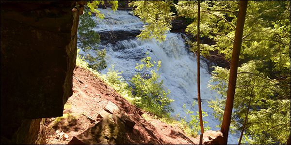A view of Agate Falls, a waterfall, from between the trees during the summer.