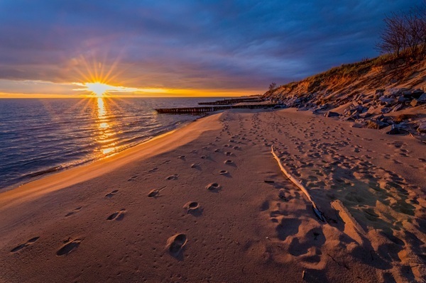 the sun sets on Lake Michigan, a few sets of footsteps mark the shoreline at Ludington State Park