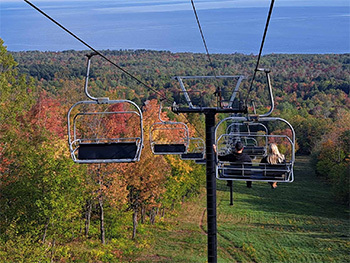 couple riding on chairlift surrounded by fall color