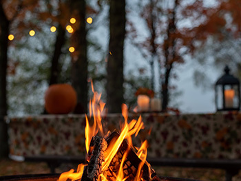 campfire with fall-decorated picnic table in the background