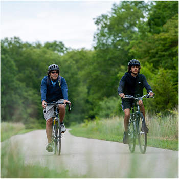 Two men riding their bikes along a paved trail