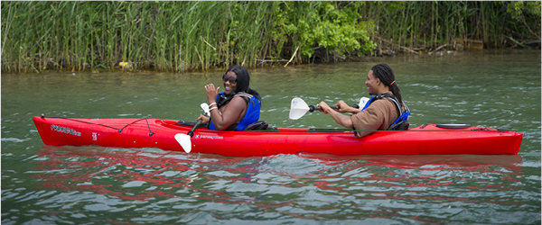 Two people smiling as they kayak in a river