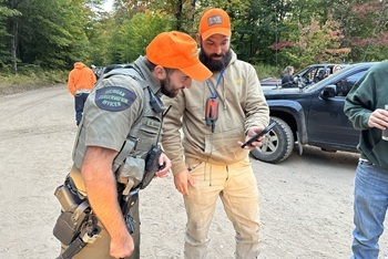 A male DNR conservation officer checks a man's bear hunting license while on patrol in Schoolcraft County, Michigan